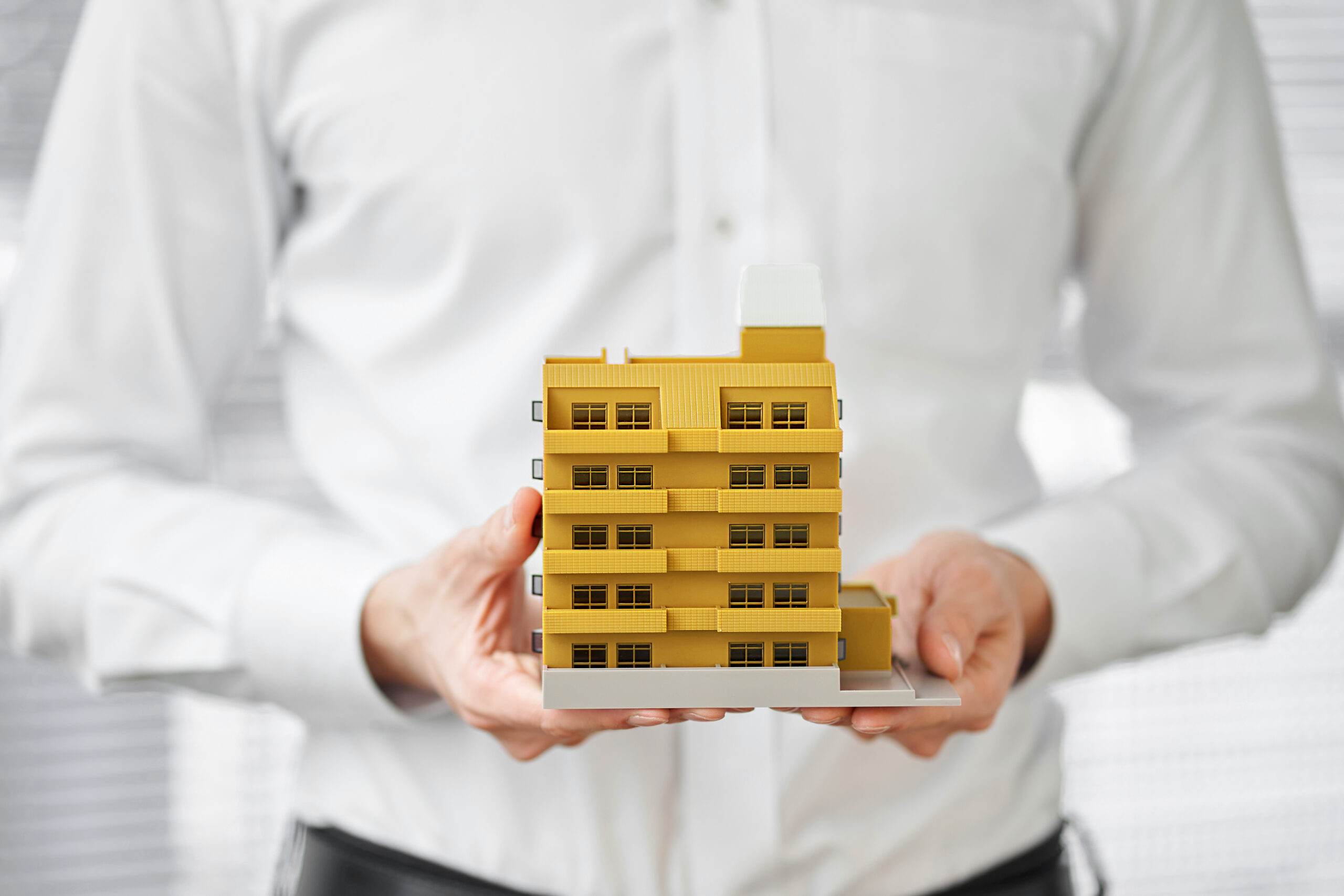 Hands of an Asian man holding an architectural model of an apartment